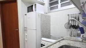 Eine kleine Küche mit Kühlschrank, Herd und einer Arbeitsplatte aus Granit.