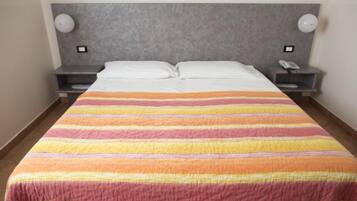 Una habitación de hotel con una cama grande, dos mesitas de noche y un cabecero.