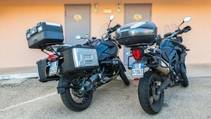 Two motorcycles parked in front of a building with two doors, each door has a number plate. - Autohotel (Formello)