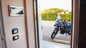 A doorway leading to a parking area with a motorcycle parked outside. - Autohotel (Formello)