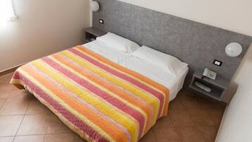 A hotel room with a bed, a nightstand, a lamp, and a telephone.