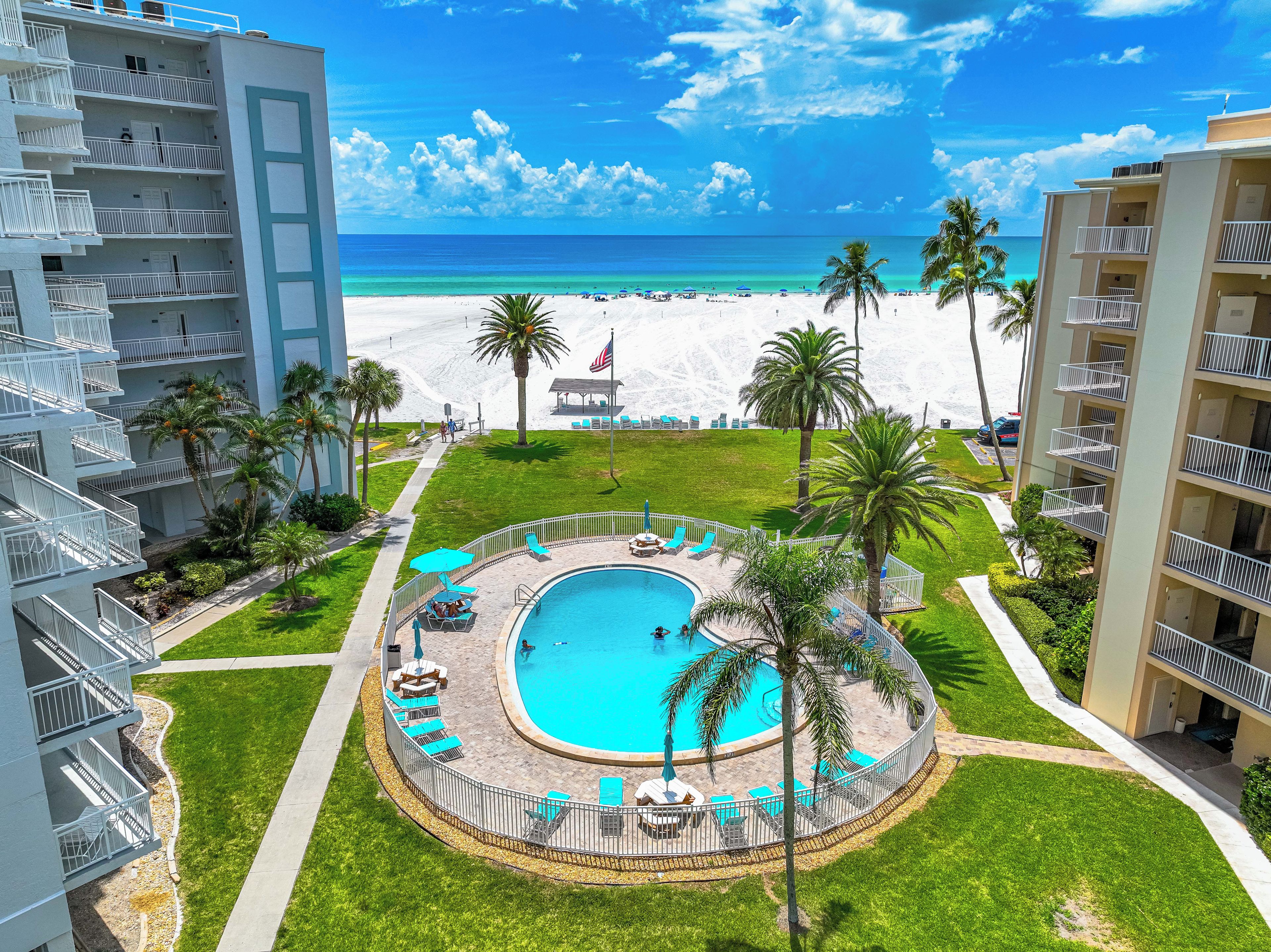 A resort with a pool, beach, and palm trees.