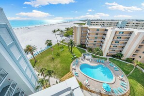A hotel with a pool, beach view, and multiple balconies.