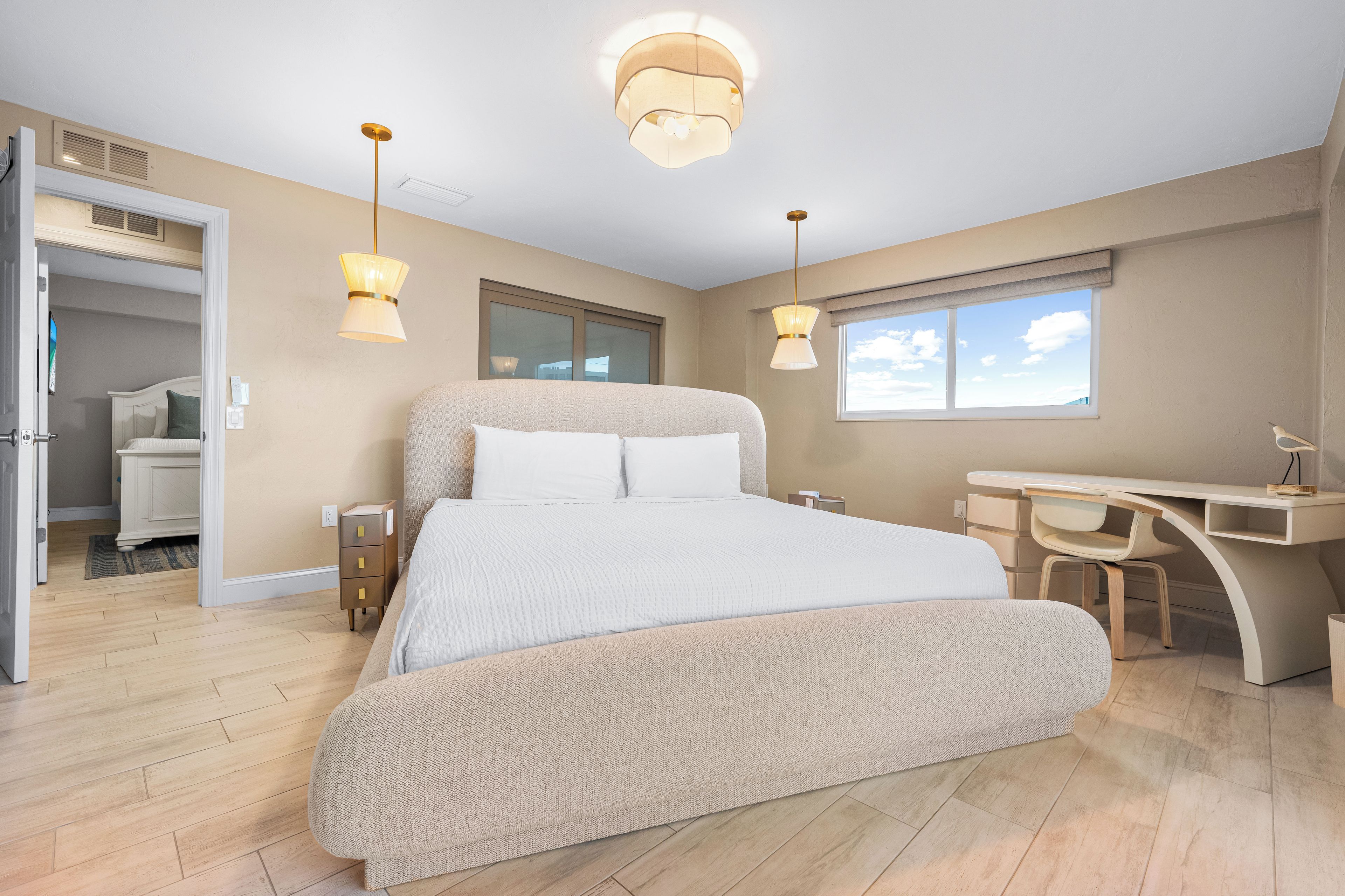 A modern bedroom with a large bed, a desk, and two pendant lights.