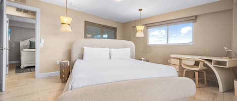 A modern bedroom with a large bed, a desk, and two pendant lights.