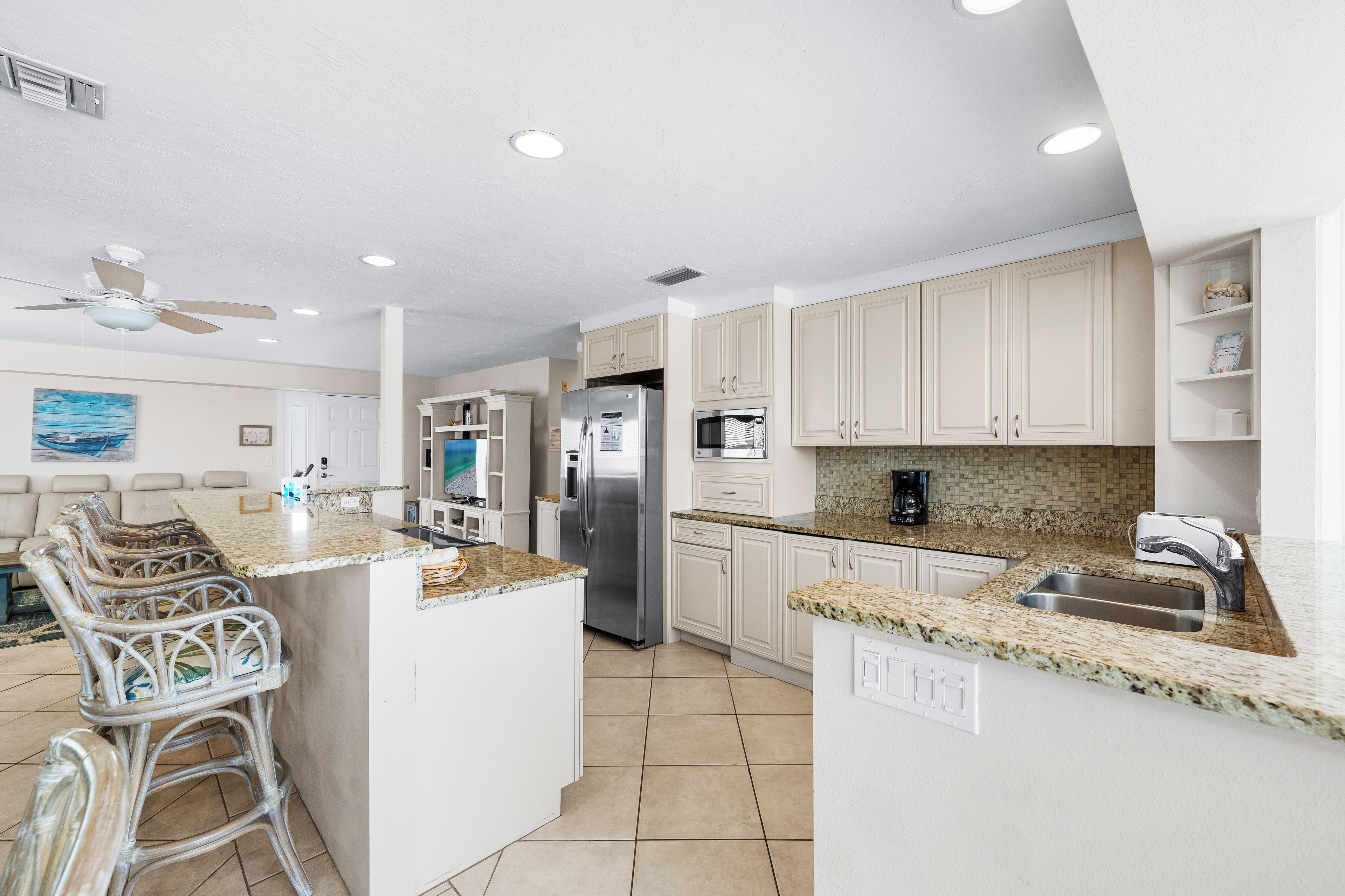 A modern kitchen with white cabinetry, granite countertops, and a central island.