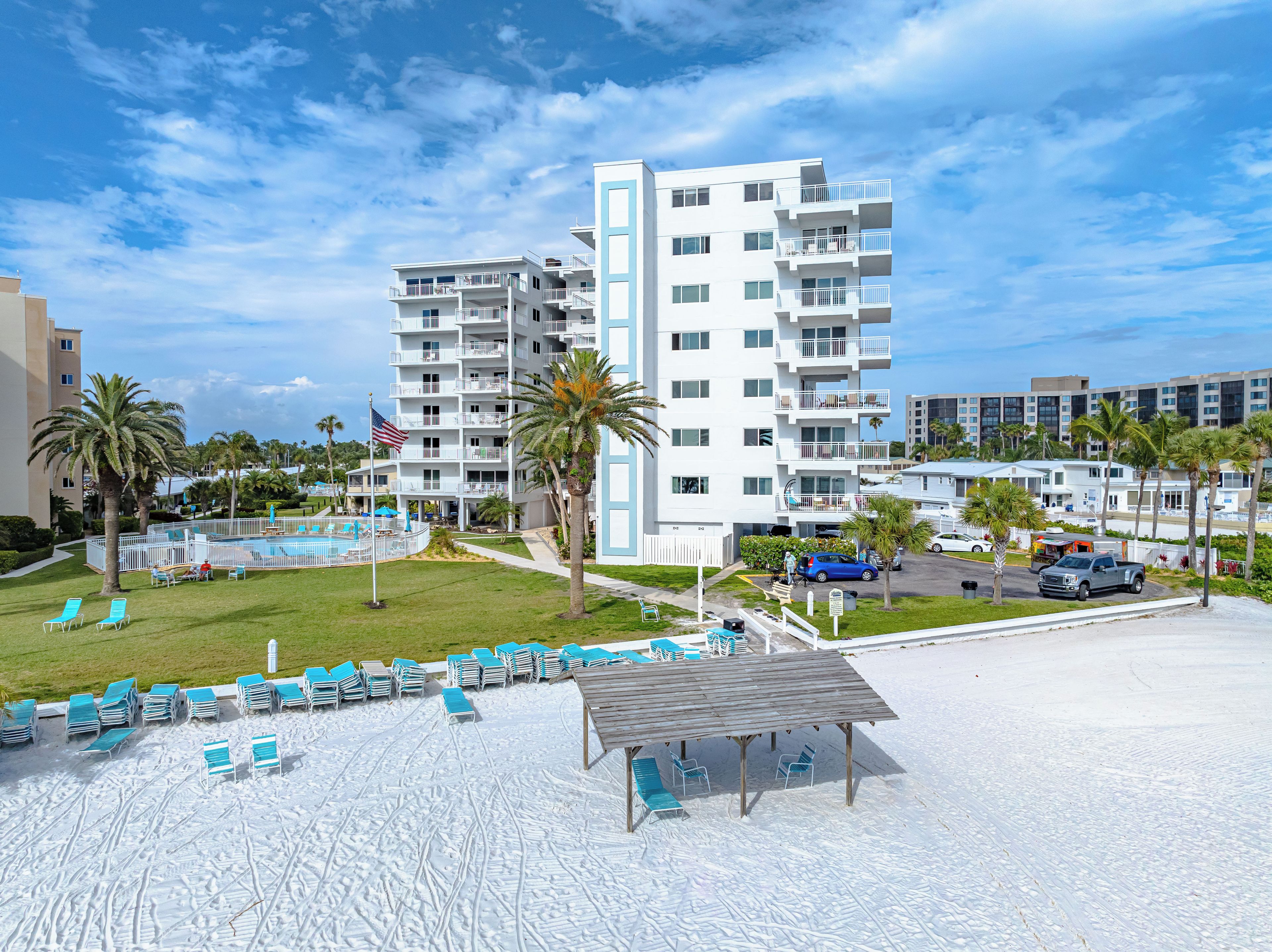 Un complexe hôtelier doté d’une piscine, de chaises longues et d’un bâtiment comportant plusieurs balcons.