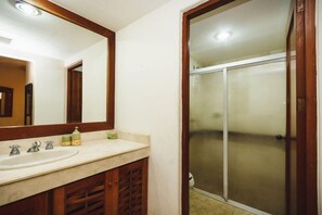 A bathroom with a sink, mirror, and shower.