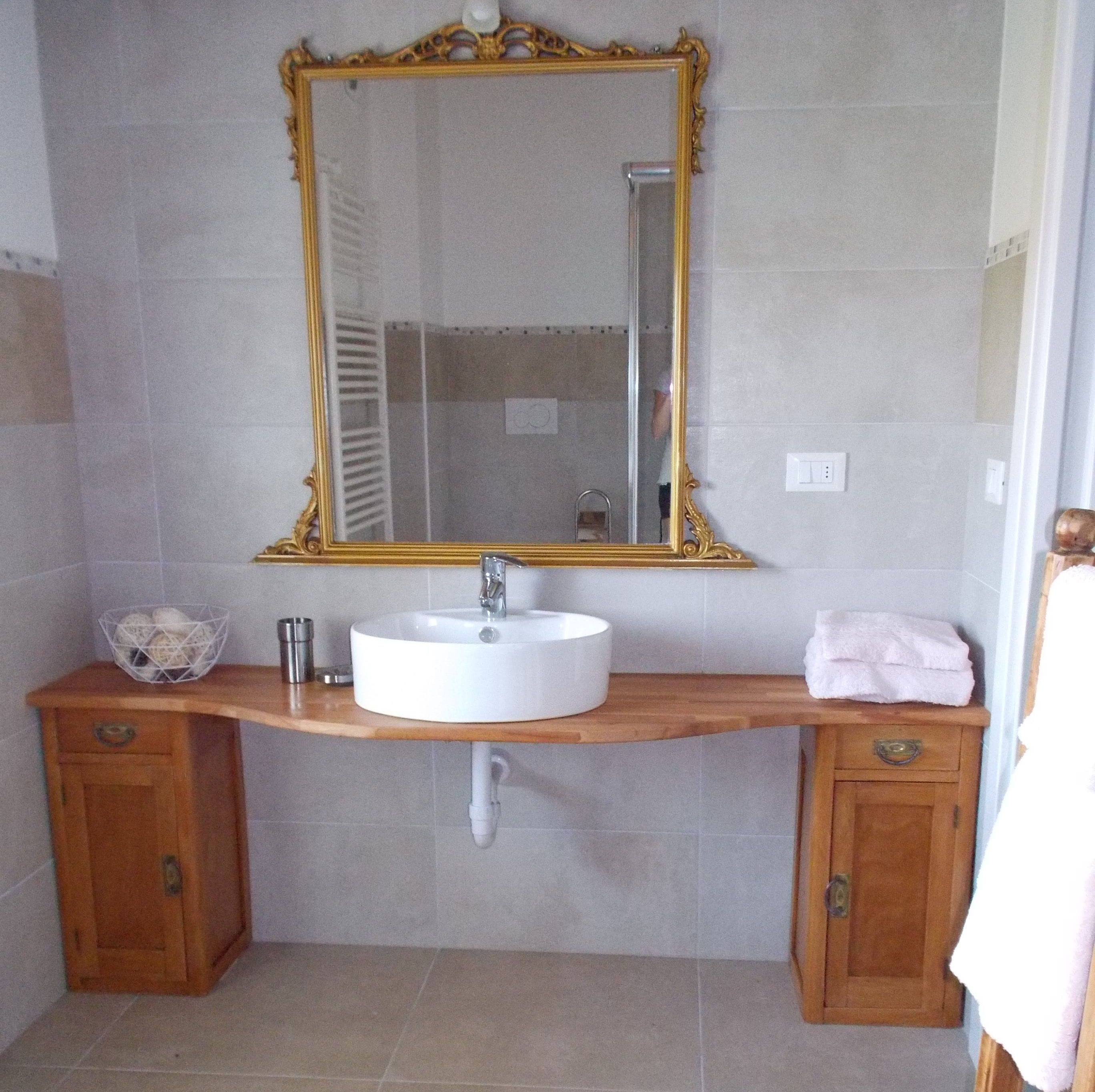 Une salle de bain avec un grand miroir, un lavabo rond, des meubles en bois et un porte-serviettes.