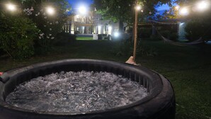 Ein Whirlpool in einem Garten mit Blick auf ein Gebäude im Hintergrund.