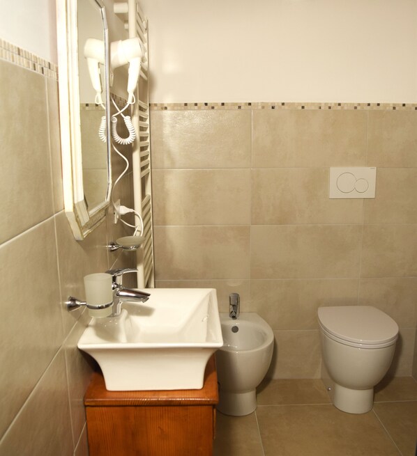 Un baño con lavamanos, espejo, secador de pelo y retrete.