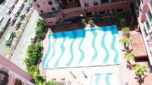 An aerial view of a hotel with a swimming pool, multiple balconies, and surrounding greenery. - Ideal Holiday Apartment Marina Court (Kota Kinabalu)