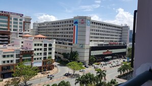 A multi-story hotel with a prominent flag on the building, a parking area, and surrounding buildings. - Ideal Holiday Apartment Marina Court (Kota Kinabalu)