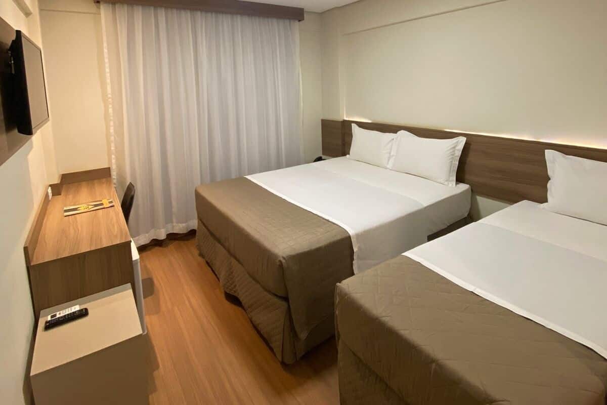 Une chambre d’hôtel avec deux lits, un bureau et une télévision.