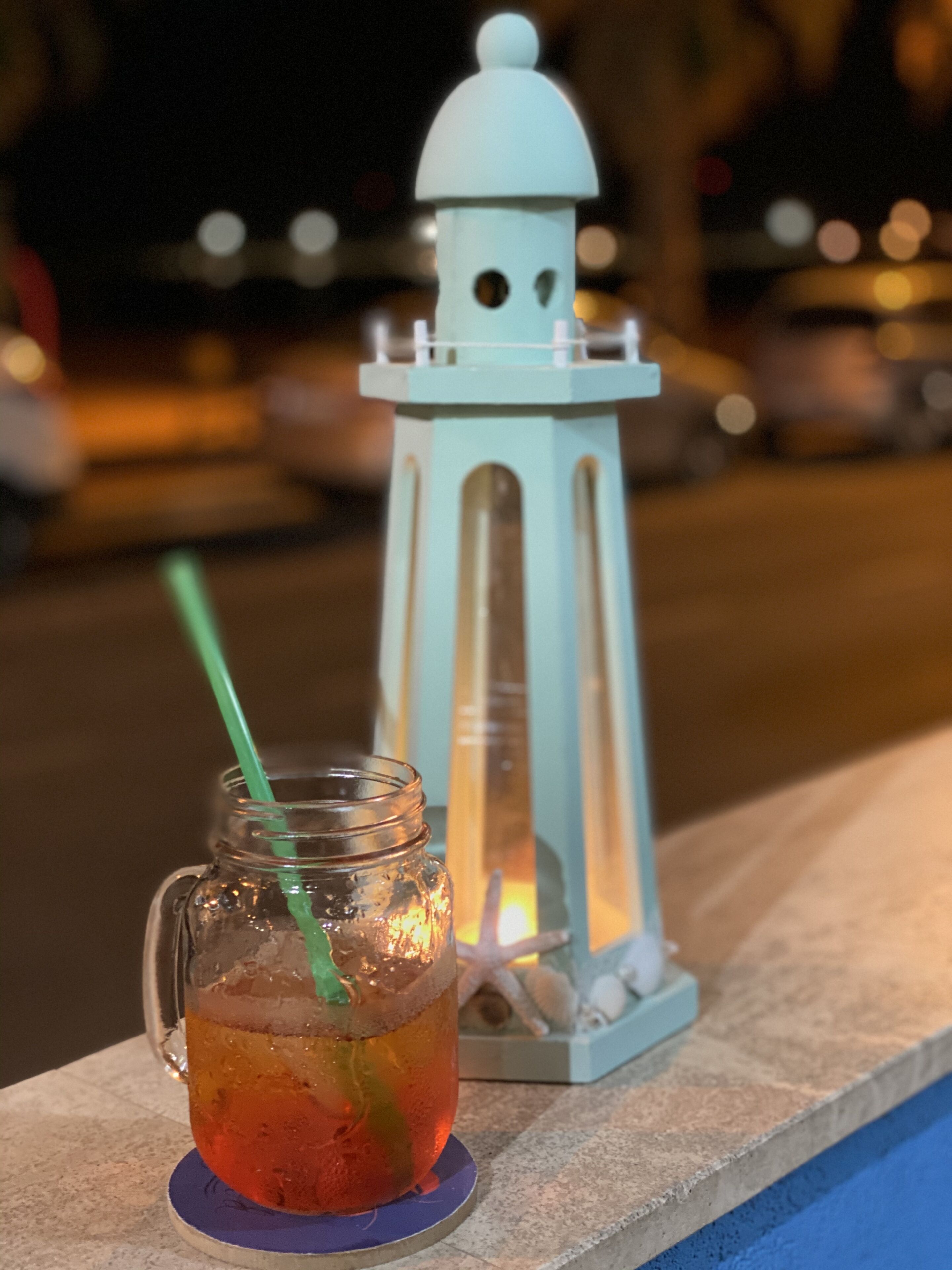 A glass mug with a straw and a decorative lantern beside it.