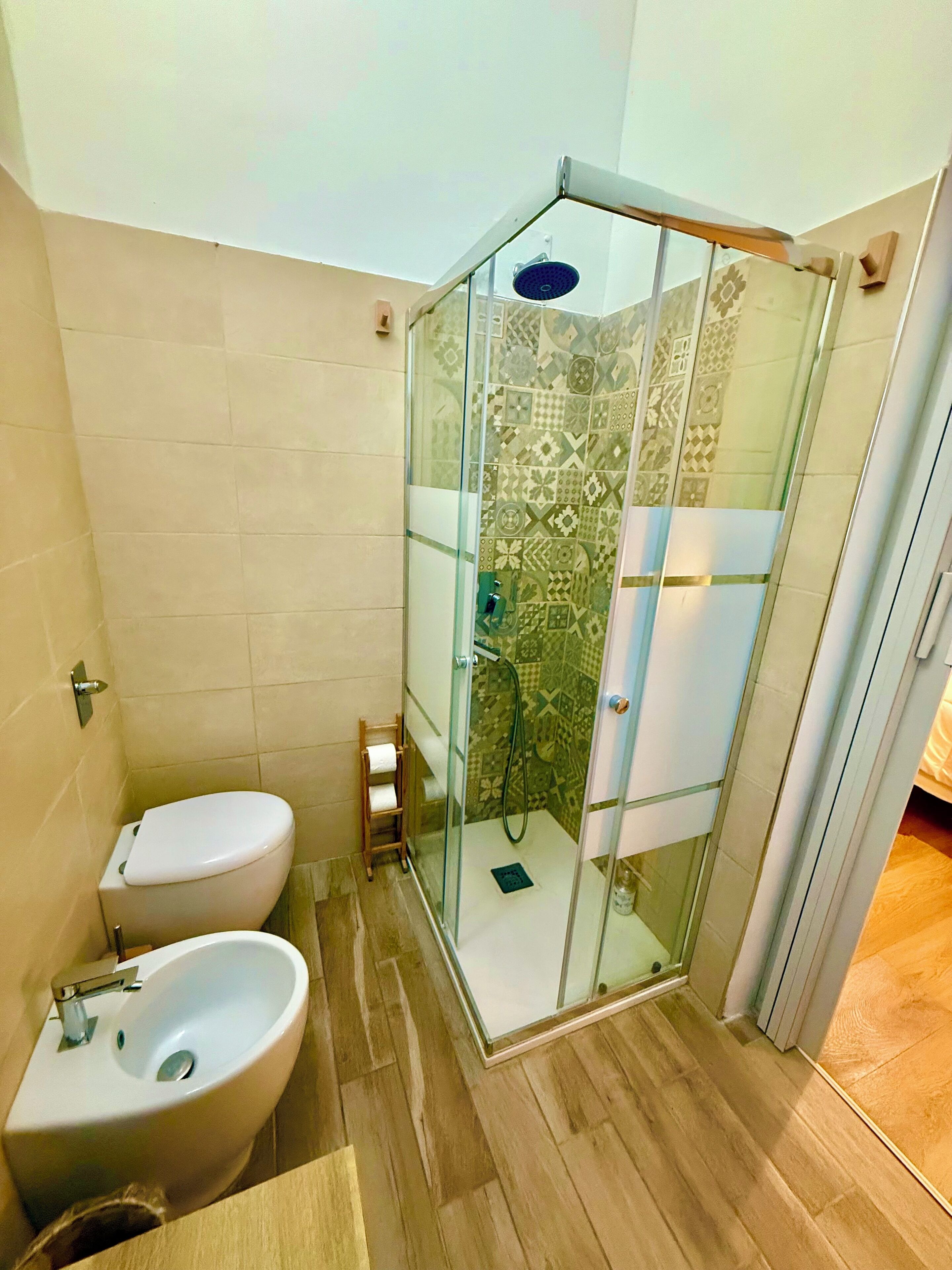 A bathroom with a glass-enclosed shower, a toilet, and a sink.
