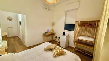 Un dormitorio con cama, televisión, escritorio y armario.