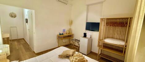 Quarto com cama, televisão, escrivaninha e guarda-roupa.