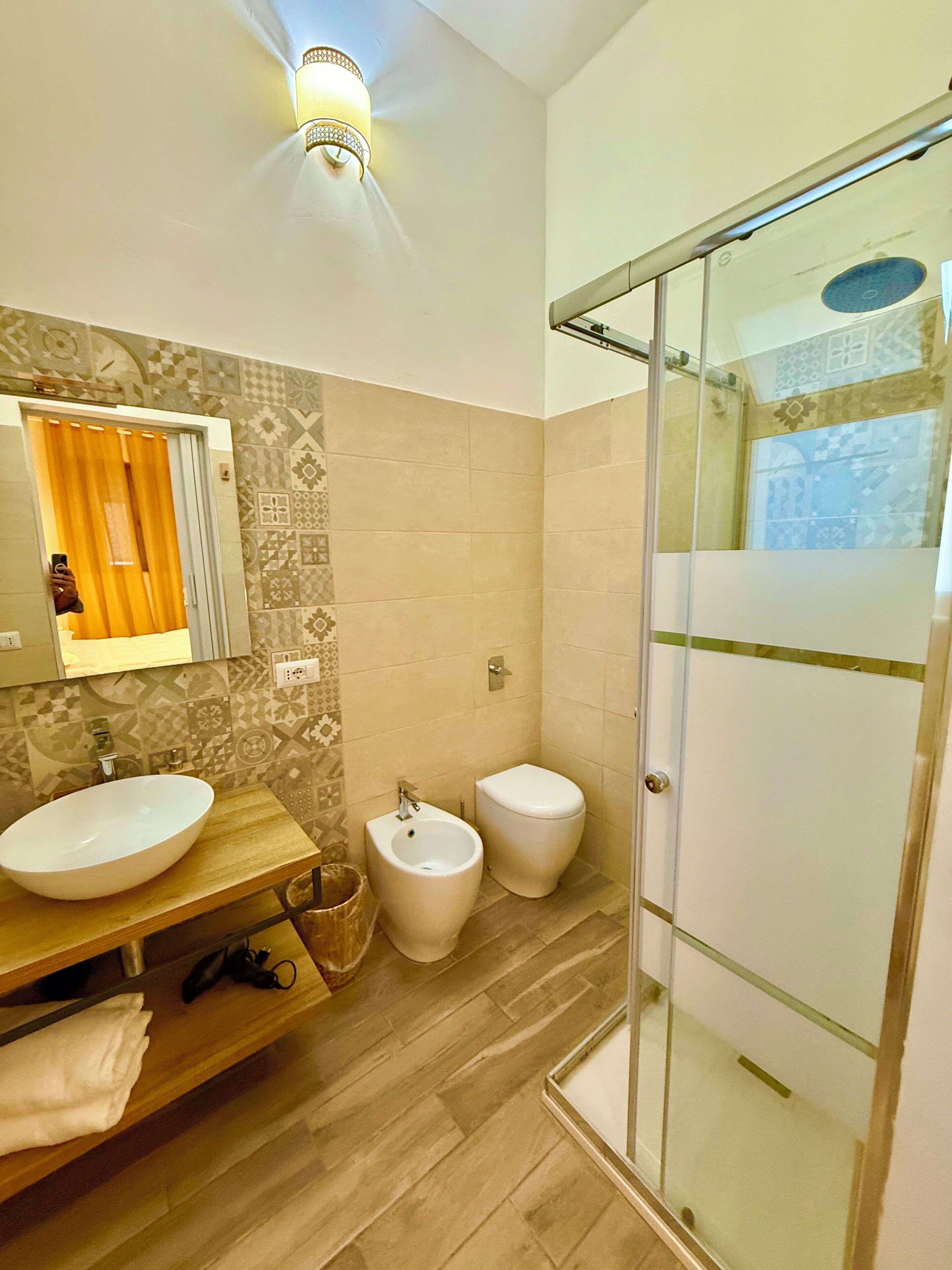 Een badkamer met een groot wastafel, bidet, toilet en een douche met glazen wanden.