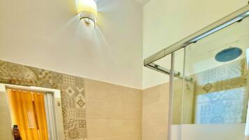 A bathroom with a large sink, bidet, toilet, and a glass-enclosed shower.