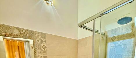 Een badkamer met een groot wastafel, bidet, toilet en een douche met glazen wanden.