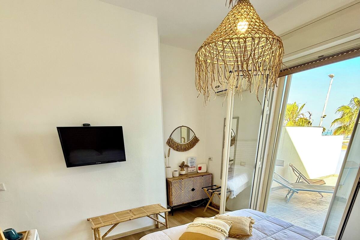 Une chambre à coucher avec un lit, une télévision, une table de chevet, un miroir et une vue sur l’extérieur.