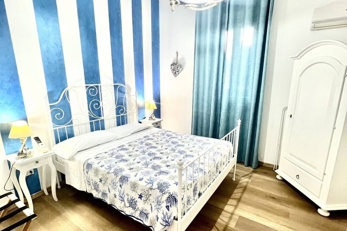 Une chambre à coucher avec un lit, une table de chevet, une commode et un lustre.