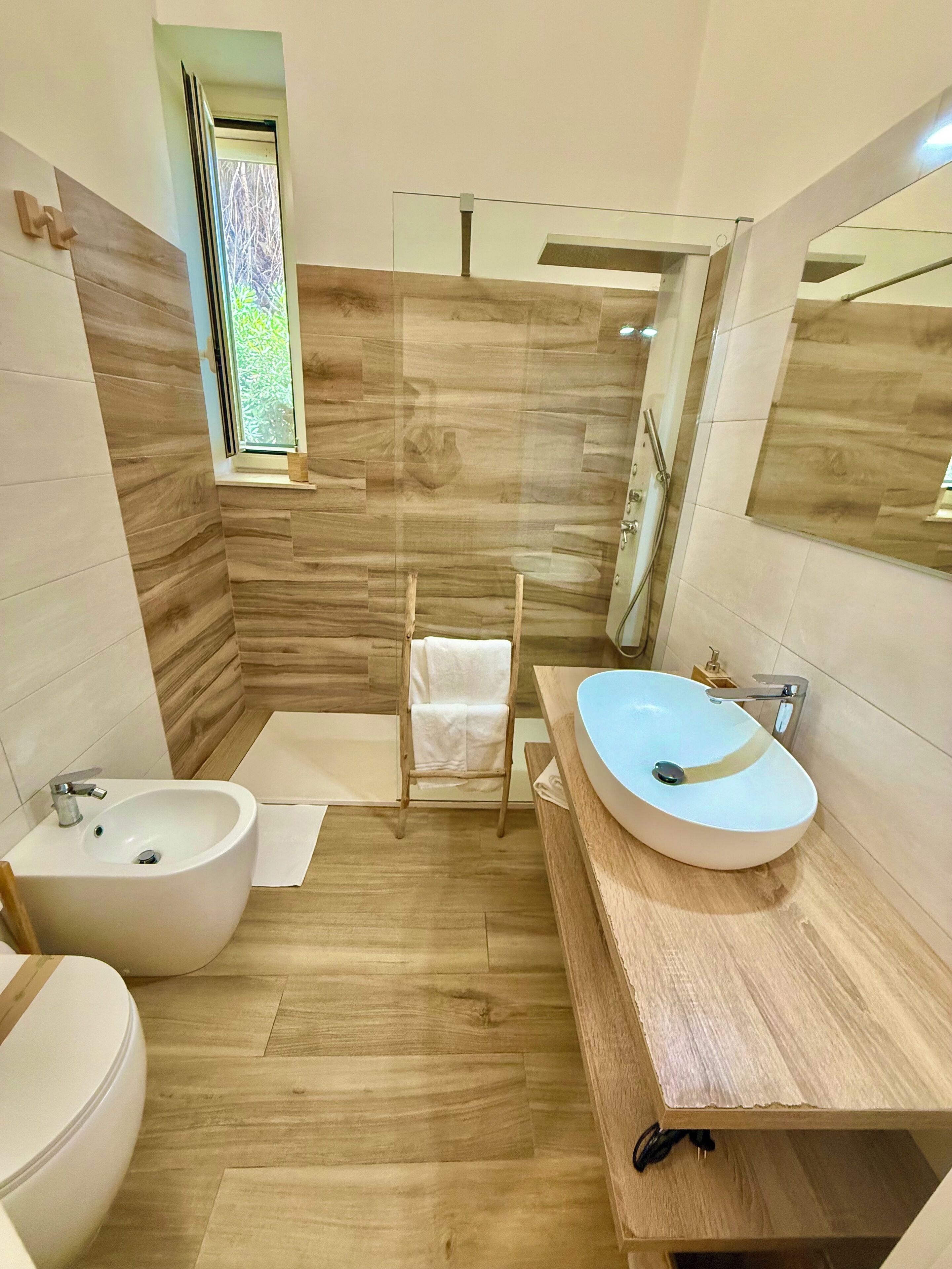 A modern bathroom with a bidet, a large sink, and a mirror.