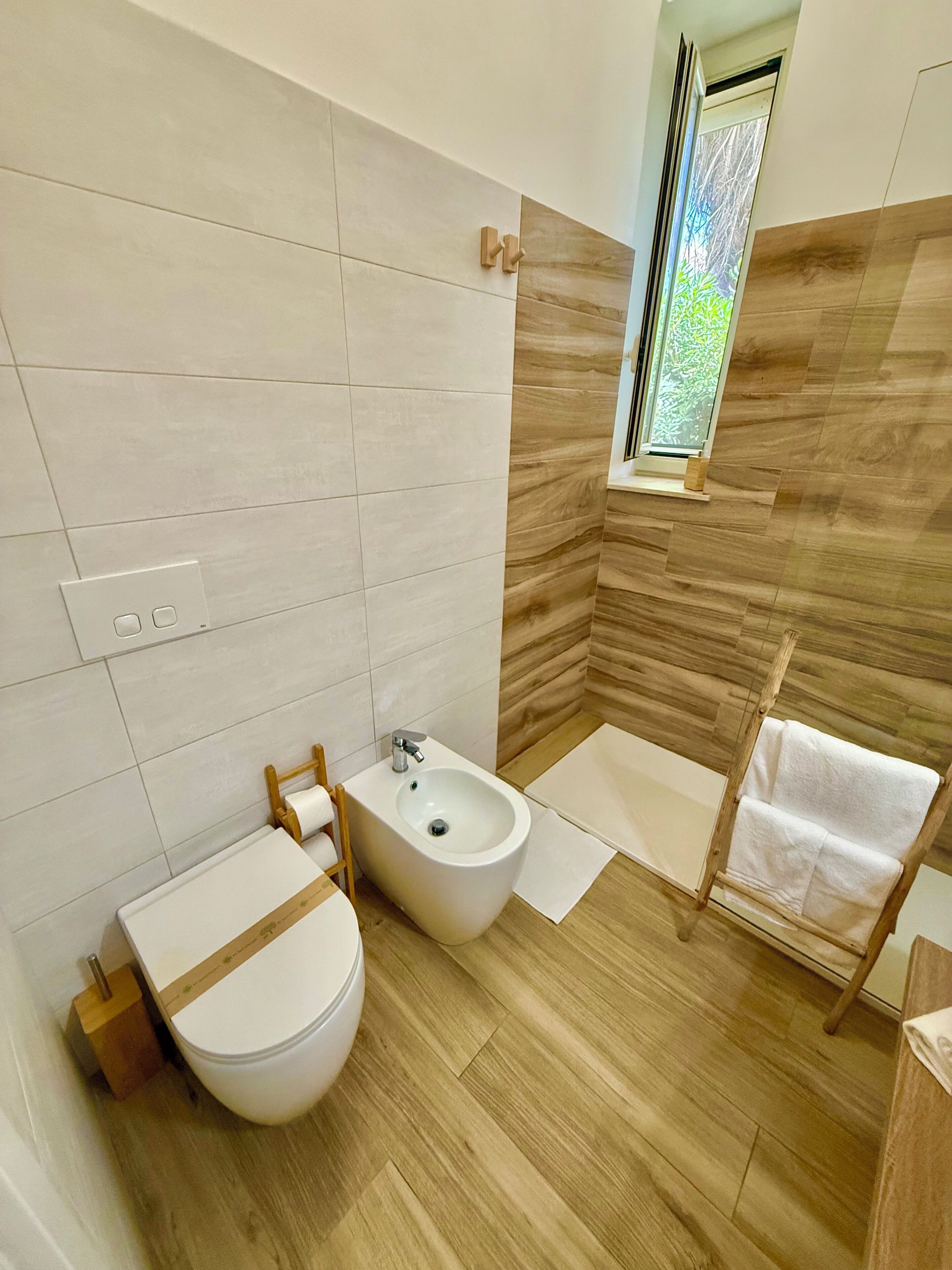 Une salle de bain moderne avec des toilettes, un bidet et un plancher en bois.