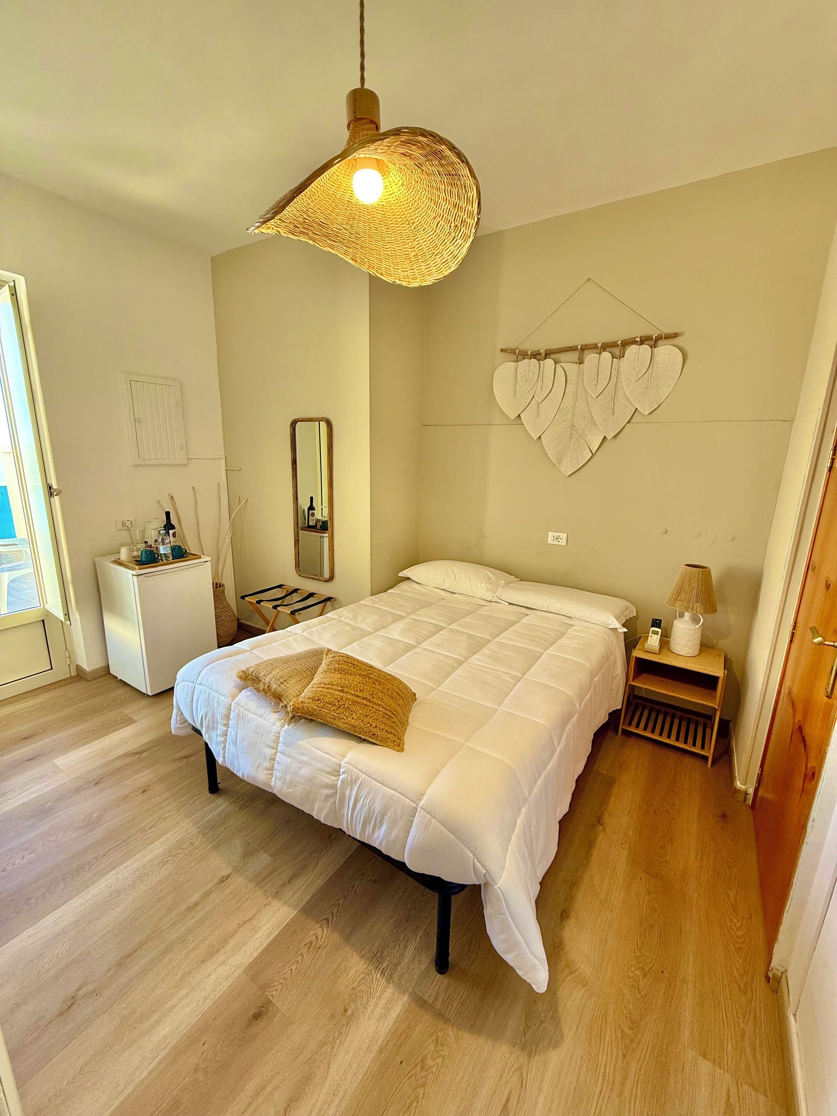 A bedroom with a bed, bedside table, lamp, and a hanging heart decoration.