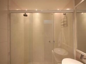 Ein Badezimmer mit Duschkabine, Waschbecken und Spiegel.