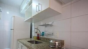 A compact kitchen with a granite countertop, a built-in oven, and white cabinets. - GoHouse Djalma 401 A (Rio de Janeiro)