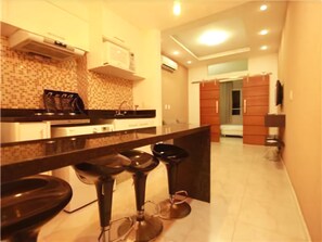 A modern kitchen with a central island, bar stools, and a microwave. - GoHouse Domingos 403 (Rio de Janeiro)