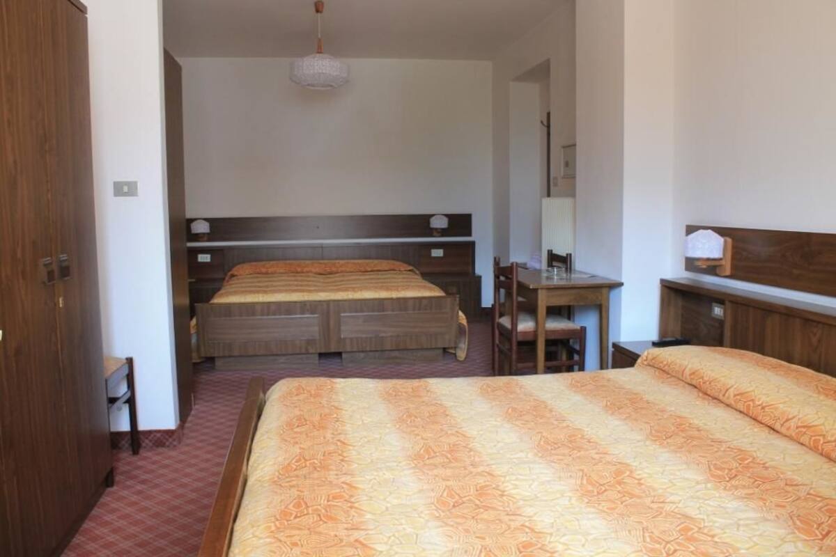 A hotel room with two beds, a desk, and a chair.