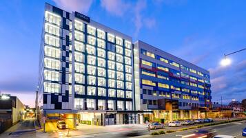 A modern hotel with a checkered facade, multiple floors, and a well-lit entrance.