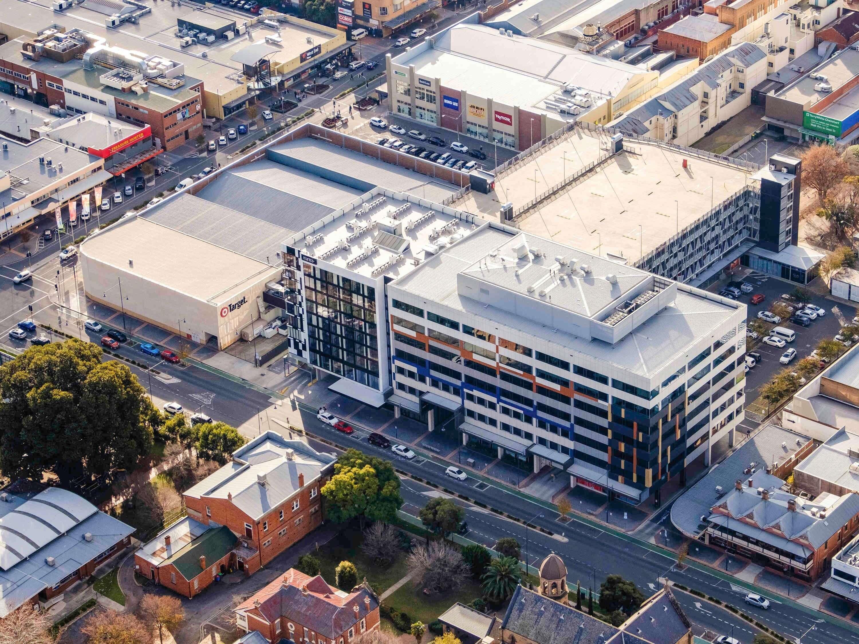 A multi-story building with a flat roof, large windows, and a parking lot.