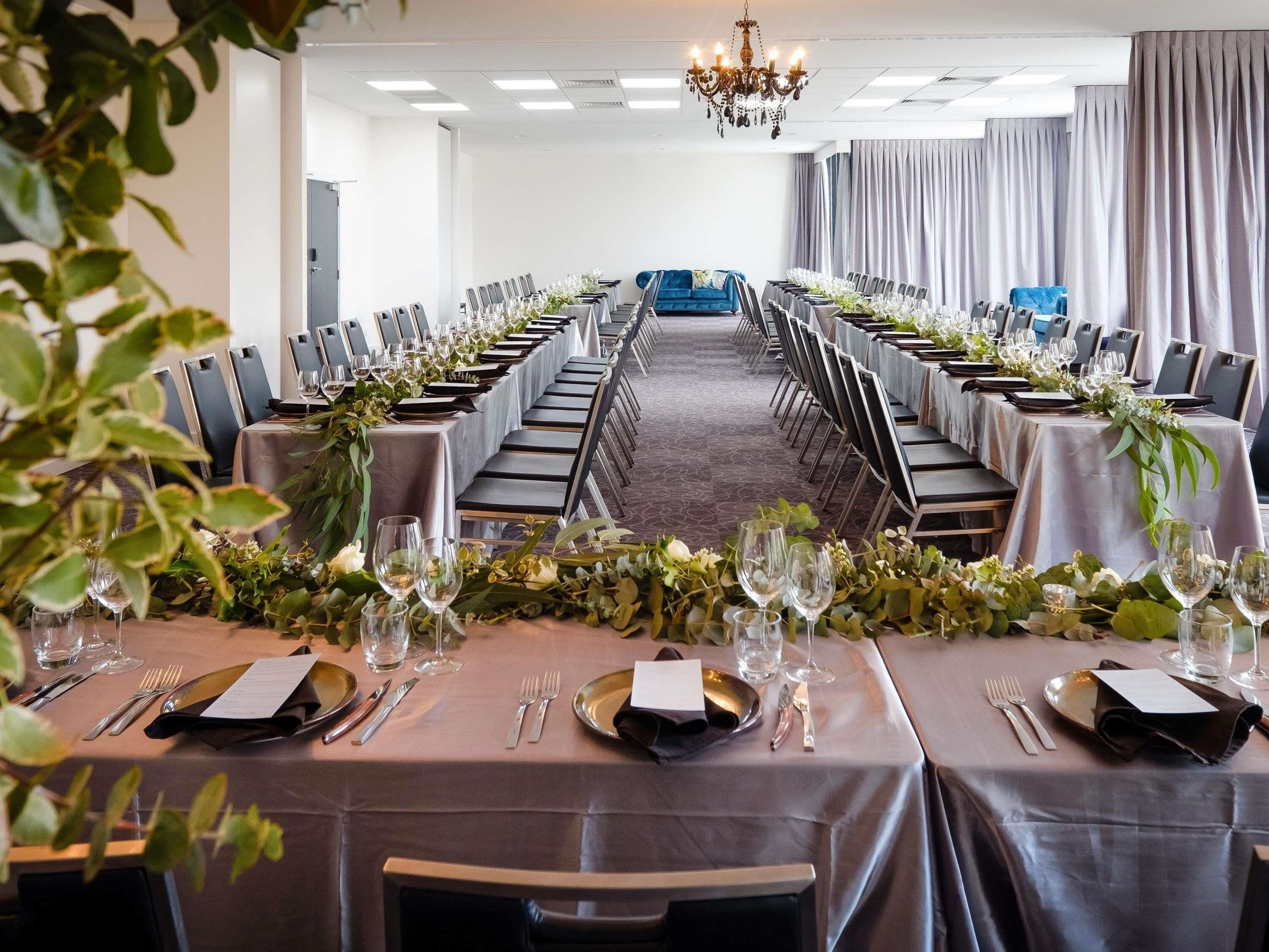 A conference room with long tables, chairs, and a chandelier.
