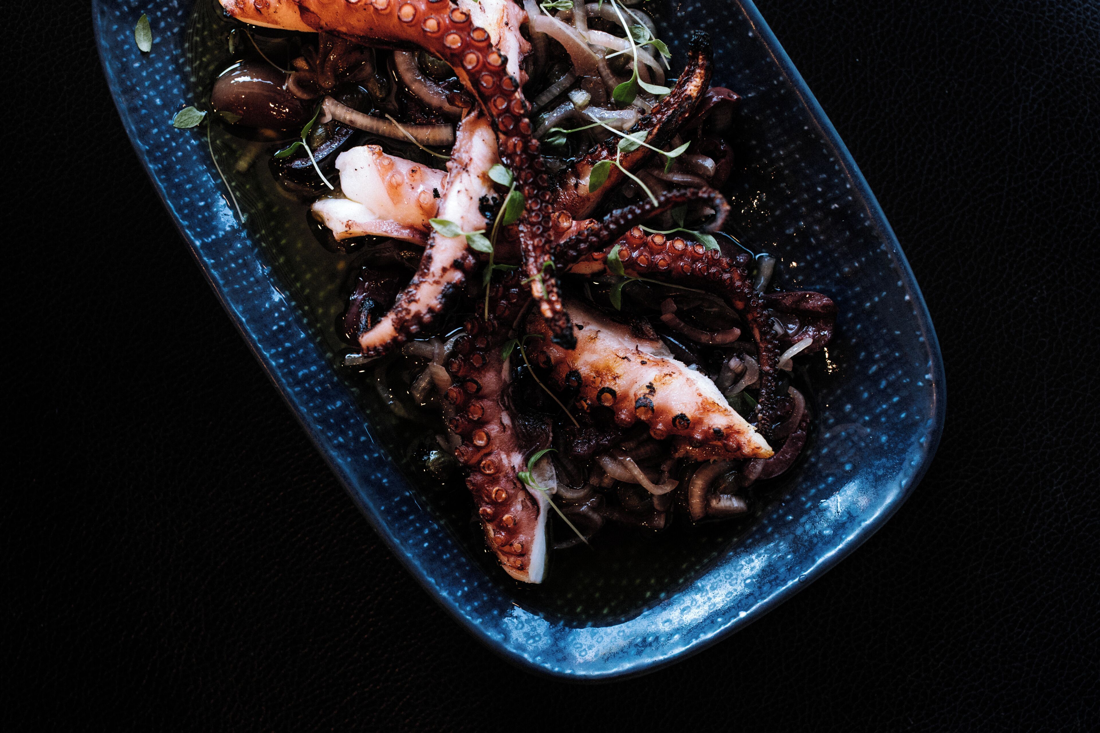 A dish of octopus with olive oil and herbs.
