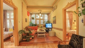 Sala de estar com sofá, televisão e plantas em vasos.