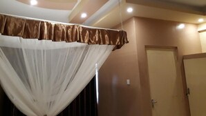 Une pièce dotée d’un plafond aux lignes courbes, d’un éclairage encastré et d’une porte située au fond.