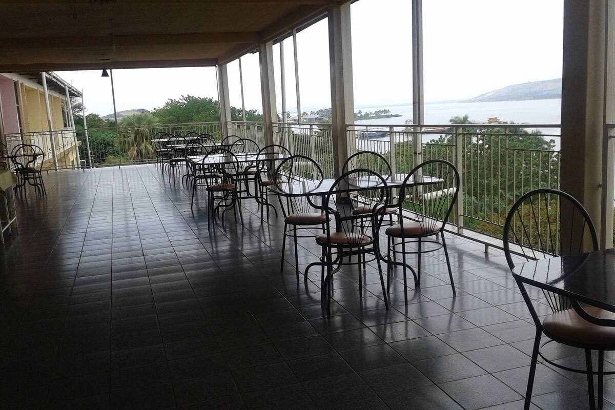 A covered terrace with tiled flooring and metal-framed tables and chairs.
