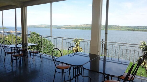Une terrasse couverte, dotée d’une table et de chaises, qui offre une vue sur un plan d’eau et sur des collines lointaines.