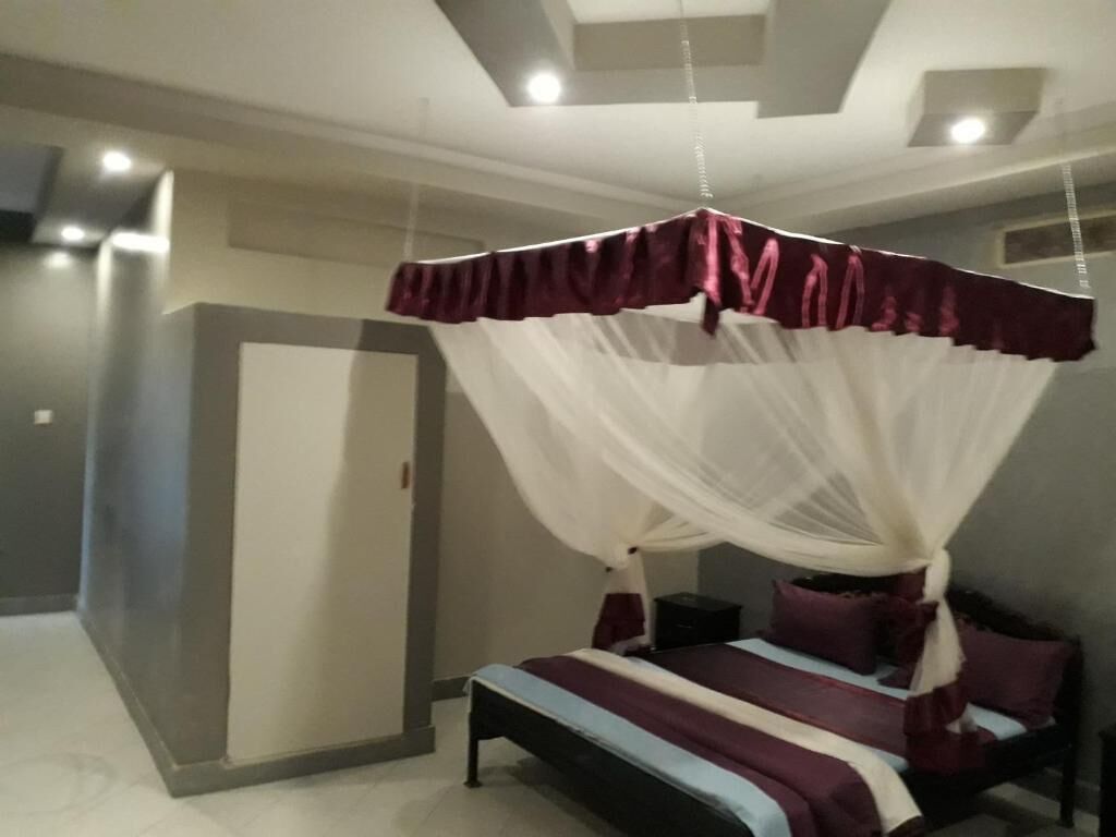 A bedroom with a four-poster bed, a bedside table, and a wardrobe.
