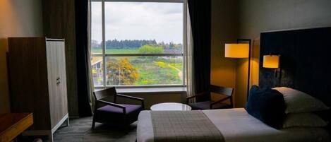 Una habitación de hotel con un ventanal grande, una cama, un escritorio y una silla.
