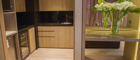 A modern kitchen with wooden cabinets, a black countertop, and a built-in oven. There is a vase with white flowers on the counter.