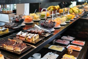 Un bufé con diversos alimentos, incluyendo postres, frutas y bebidas.