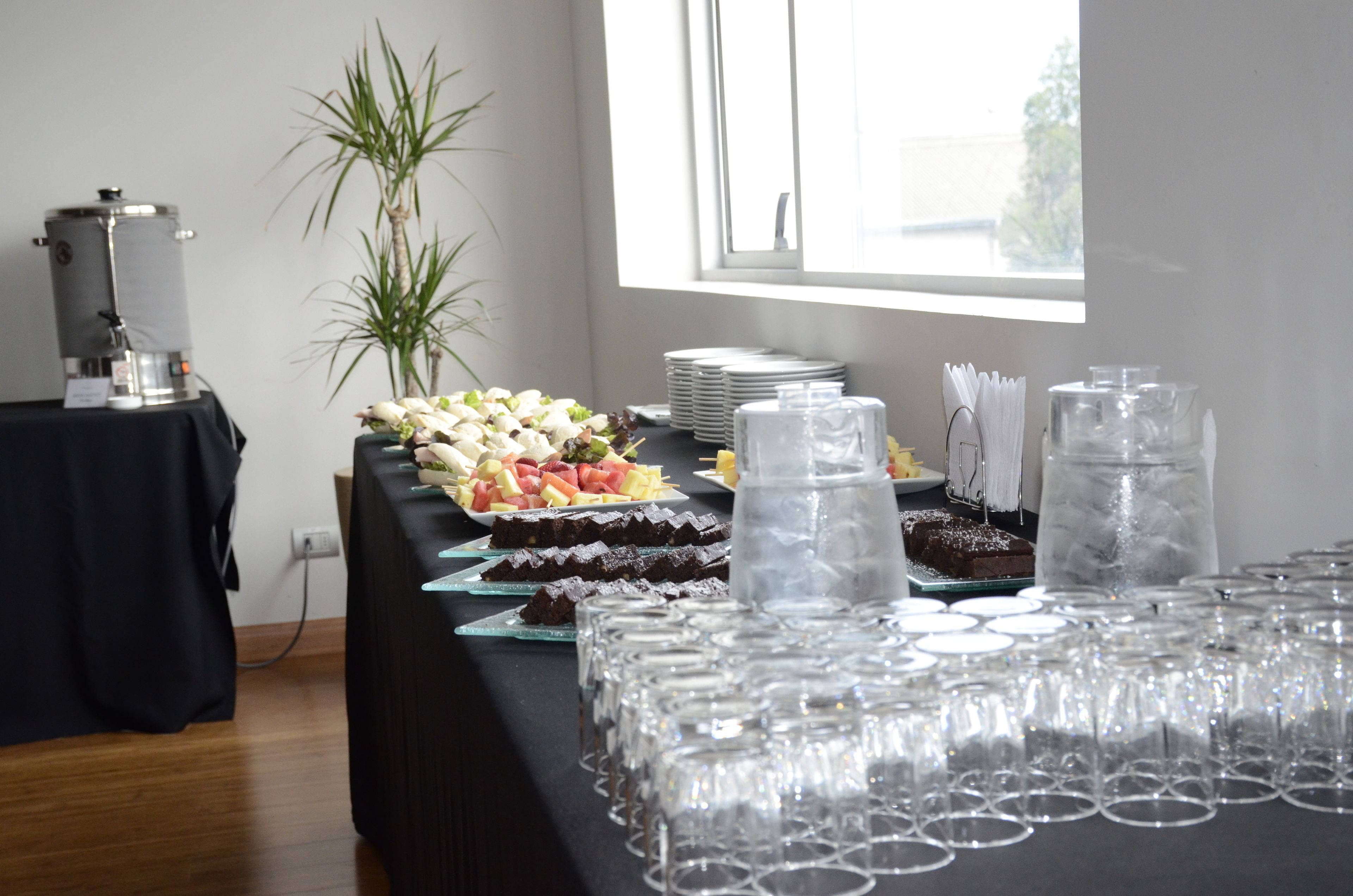 A buffet table with various food items and clear glasses.