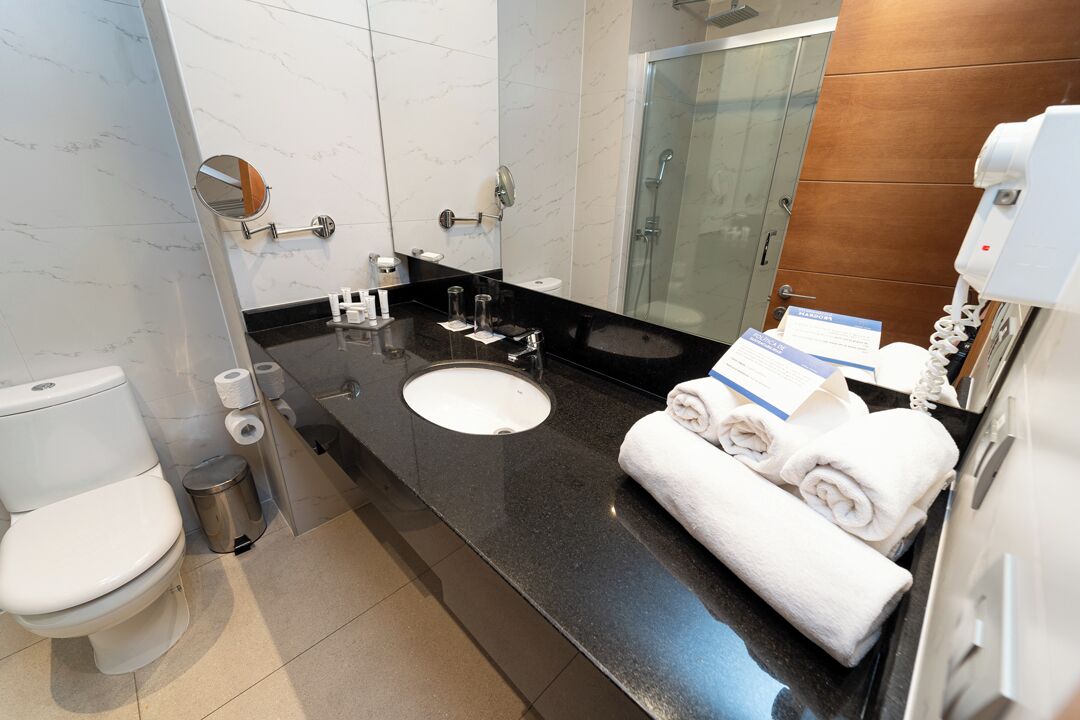A modern bathroom with a black countertop, white sink, and a glass shower enclosure.