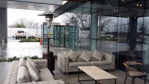 A modern lobby with a glass entrance, a beige sofa, a coffee table, and a lamp. - Hotel Parada Linares (Linares)