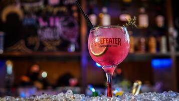 A cocktail glass labeled "Efeater London Dry Gin" on a bar counter with ice.